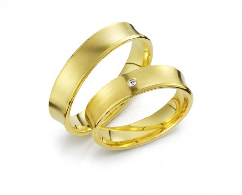 Vielsesringe i guld med en indadkurvet ringskinne med brilliantslebet diamant placeret i midten.