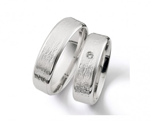 Vielsesringe i børstet og råt look med en enkelt diamant i brilliantslibning i smuk indfatning centralt på ringskinnen.